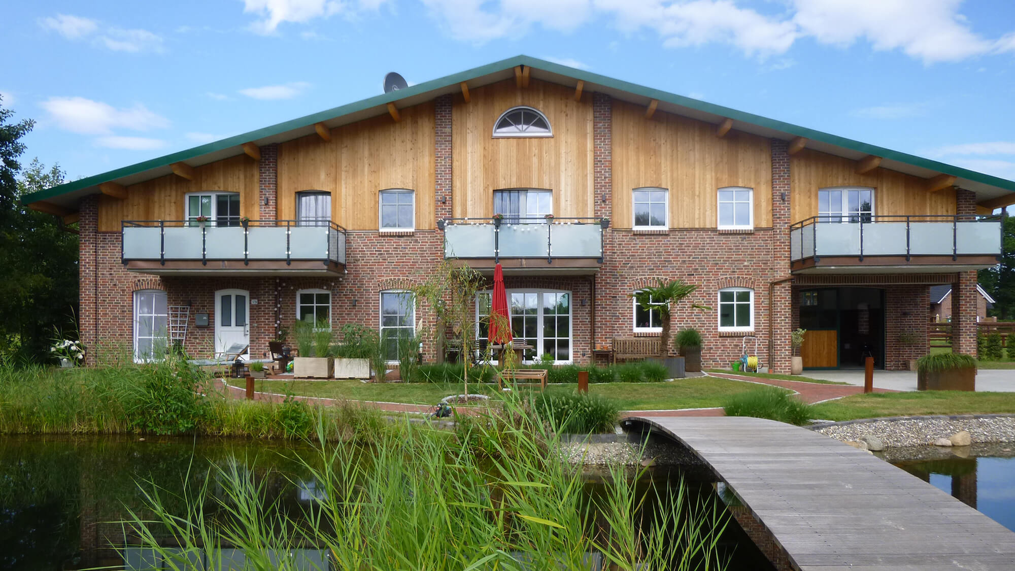 Elegantes Wohnhaus eines Gestüts mit rustikalen Ziegel- und Holzelementen, umgeben von einer idyllischen Wasserlandschaft